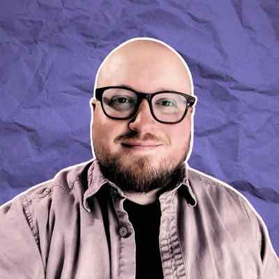 Anker Peet smiling, wearing glasses and a mauve shirt